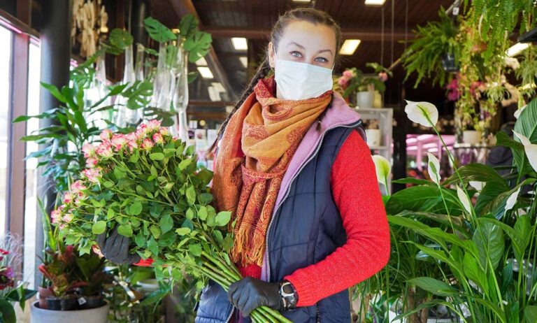 Florist employee in surgical mask protecting herself against COV