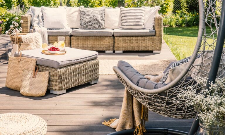 Pillows on rattan couch near table on patio with hanging chair i